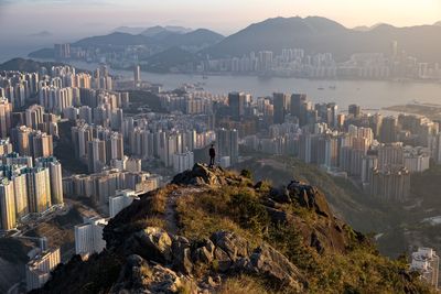 Man standing on mountain against buildings in city