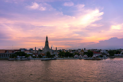 View of buildings at waterfront against cloudy sky