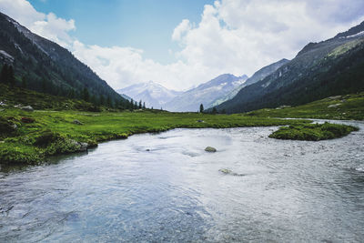 Scenic view of river by mountains against sky