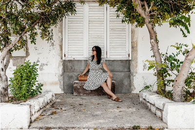 Portrait of young woman sitting on stone bench. summer, lifestyle, dress, fashion.