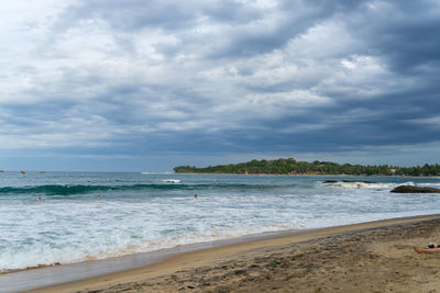 Tropical beach with palm trees. cloudy sky. arugam bay, sri lanka