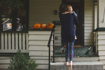 Rear view of mother carrying son while moving up on steps