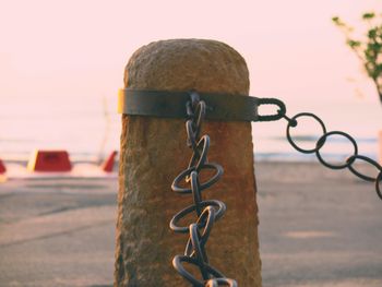 Close-up of metal chain against sky during sunset