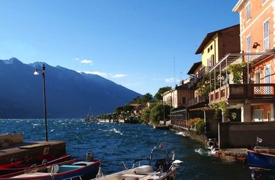 Scenic view of lake garda by buildings against blue sky