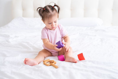 Portrait of cute girl playing with toy on bed at home