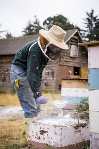 Female beekeeper using strainer while working at farm