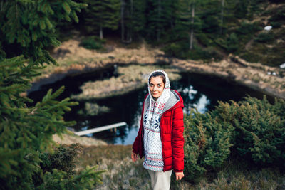 Portrait of smiling young woman standing in forest