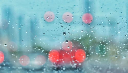 Close-up of wet window in rainy season with tail light bokeh