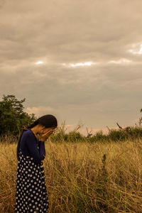 Side view of man standing on field against sky