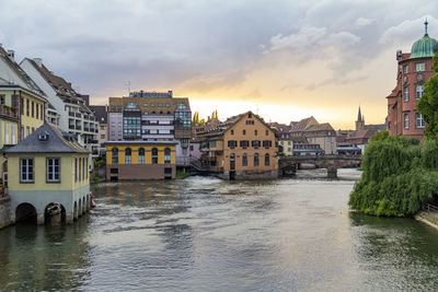 Buildings by river against sky