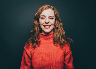 Portrait of smiling woman in orange top against gray background