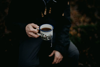 Man holding an enamel mug of tea