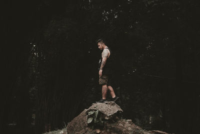 Full length of young man standing on rock in forest