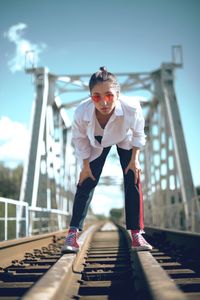 Portrait of woman wearing sunglasses standing on railroad track