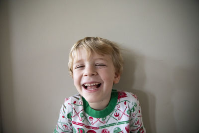 Close up portrait of laughing boy in red and green christmas pajamas