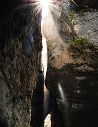 Low angle view of sun shining through rock formation