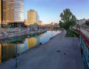 Buildings by river against sky in city