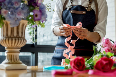 Midsection of woman arranging flowers in bouquet 