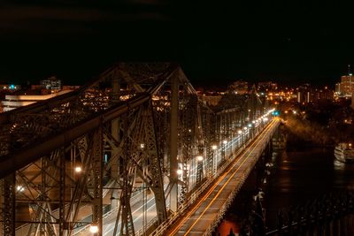 Illuminated bridge over river in city at night