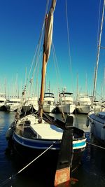 Boats moored at harbor against clear blue sky