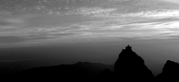 Silhouette of statue against cloudy sky