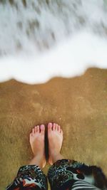 Low section of woman standing on sand