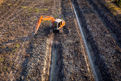 High angle view backhoe is dingging the groove garden and agricultural area evening time in thailand