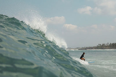 Man surfing in sea against sky