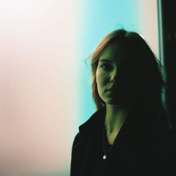 Portrait of young woman standing by window