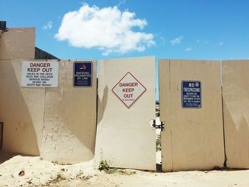 Various sign boards on fence against sky