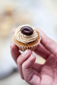 Cropped image of hand holding cupcake