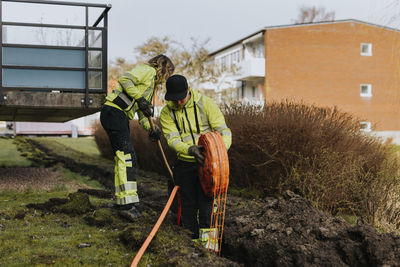 Male and female workers laying cables in trench