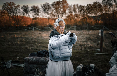 Woman standing on field against trees during winter