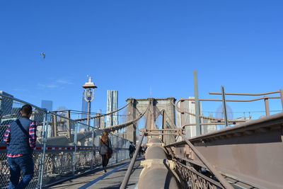 People on bridge against clear blue sky