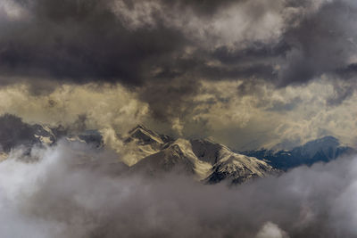 Aerial view of snowcapped mountains against cloudy sky