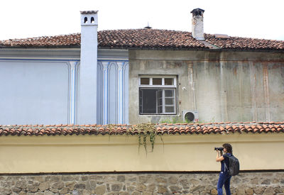 Photographer photographing while standing against house