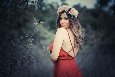 Portrait of young woman standing by tree