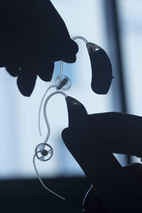 Close-up of silhouette hand holding eyeglasses