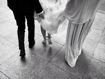 Low section of priest with bride and bridegroom walking on footpath