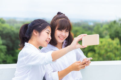 Young woman photographing while using smart phone