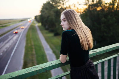 Side view of woman standing on railing