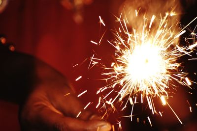 Cropped hand holding sparkler at night