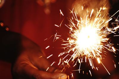 Cropped hand holding sparkler at night