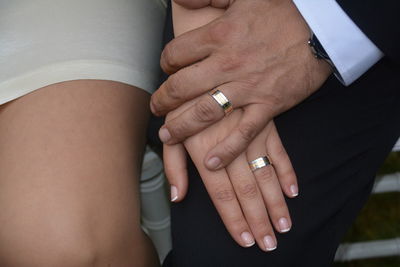 Midsection of couple holding hands sitting outdoors