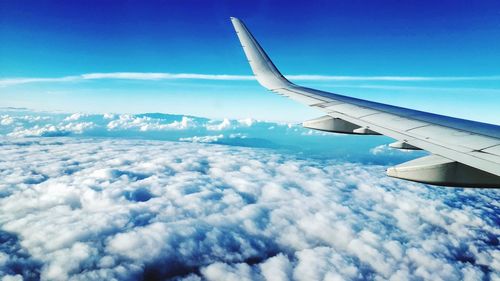Airplane flying over cloudscape against blue sky