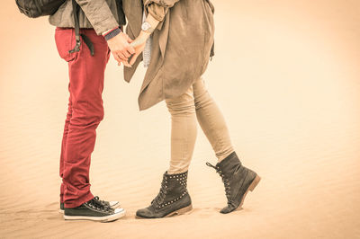 Low section of man and woman standing on beach