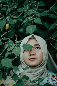 Woman in hijab standing against tree