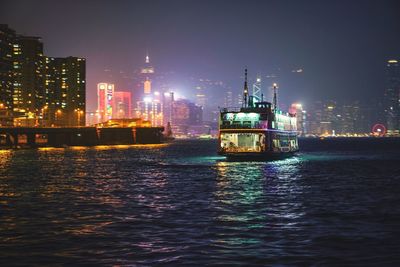 Boat sailing on river in illuminated city at night