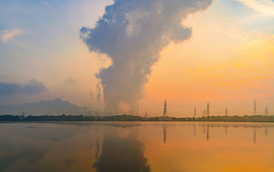 Smoke emitting from factory against sky during sunset