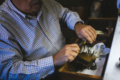 Watchmaker hands in the foreground working with an antique clock